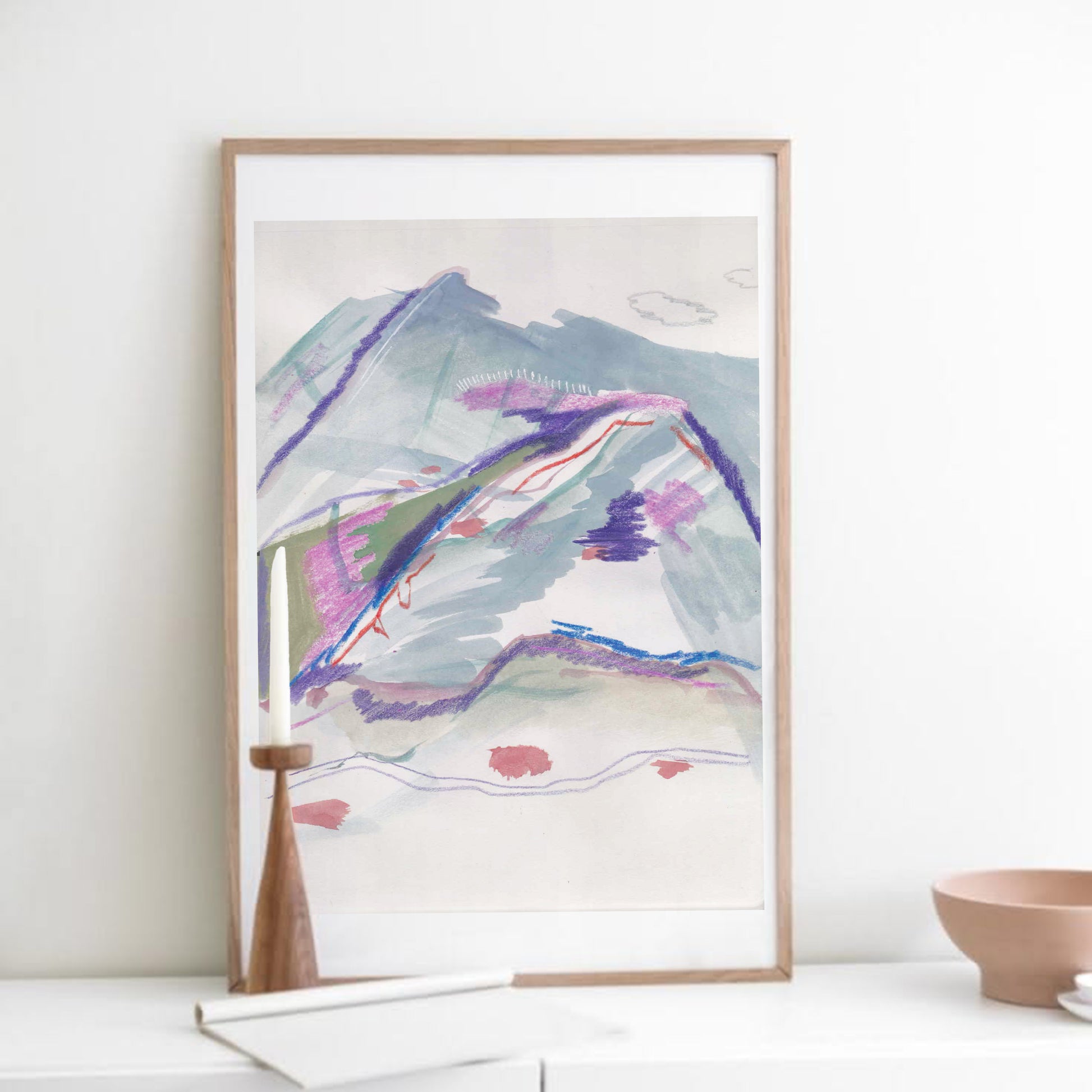 Framed abstract art print on a white wall with a bowl and books in the foreground.